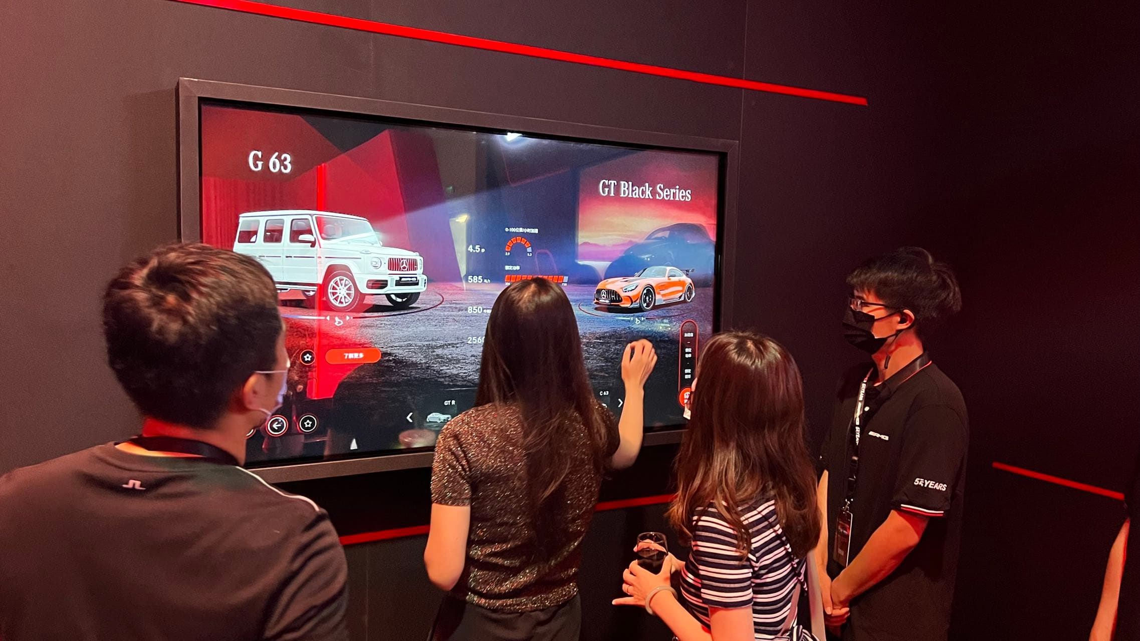 Showroom visitors exploring AMG models on the One Display touchscreen